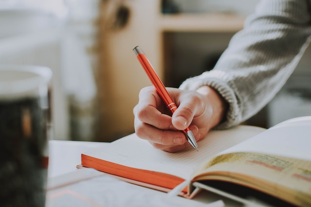 Close up of a hand holding a pen and writing in a notebook